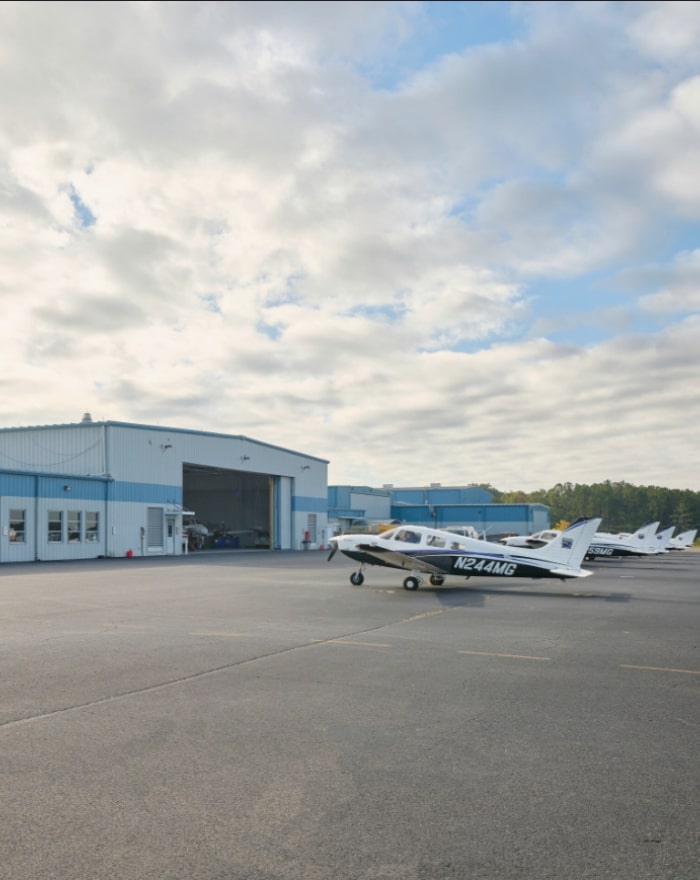 A side view of MGA's Eastman campus hangar with five planes parked in a row